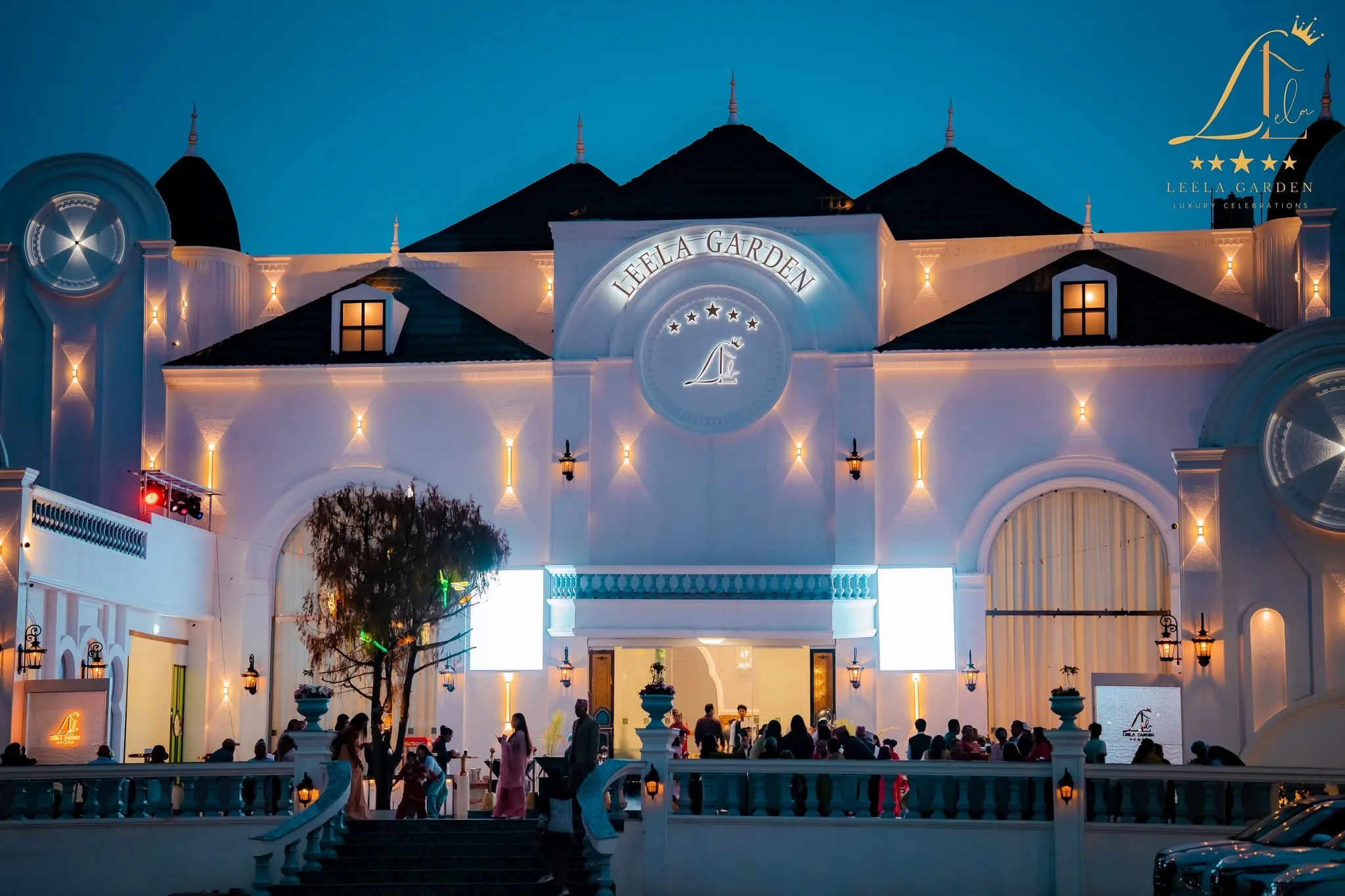 The facade lit at night, the Leela Garden crest and lettering glowing above the entrance canopy.