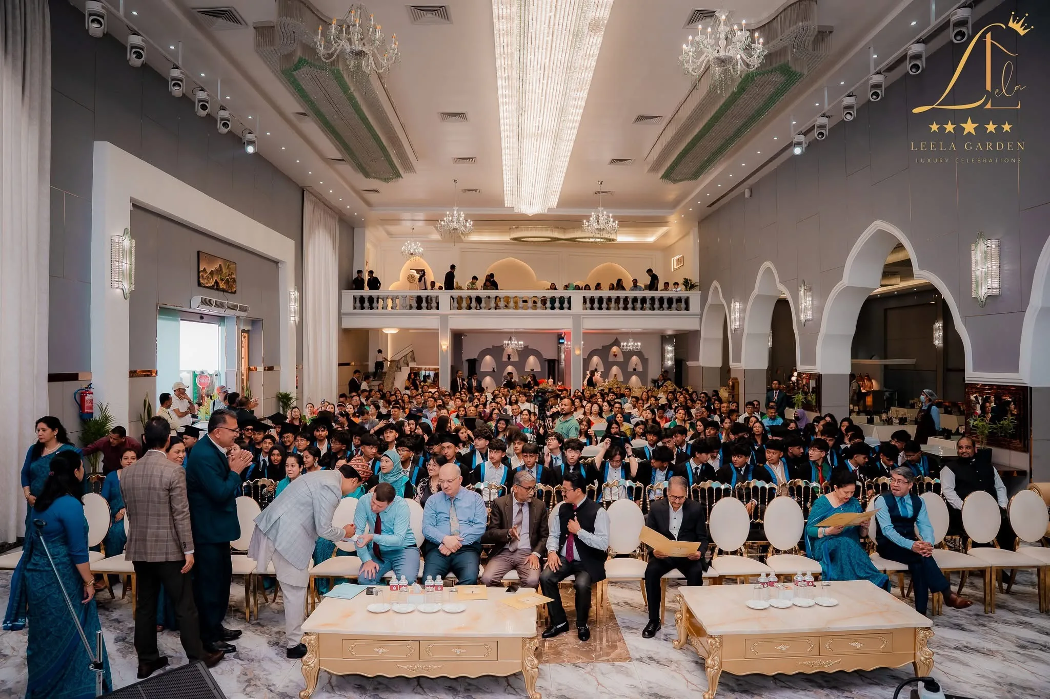 The hall filled with seated guests at a corporate gathering, low tables along the rows.