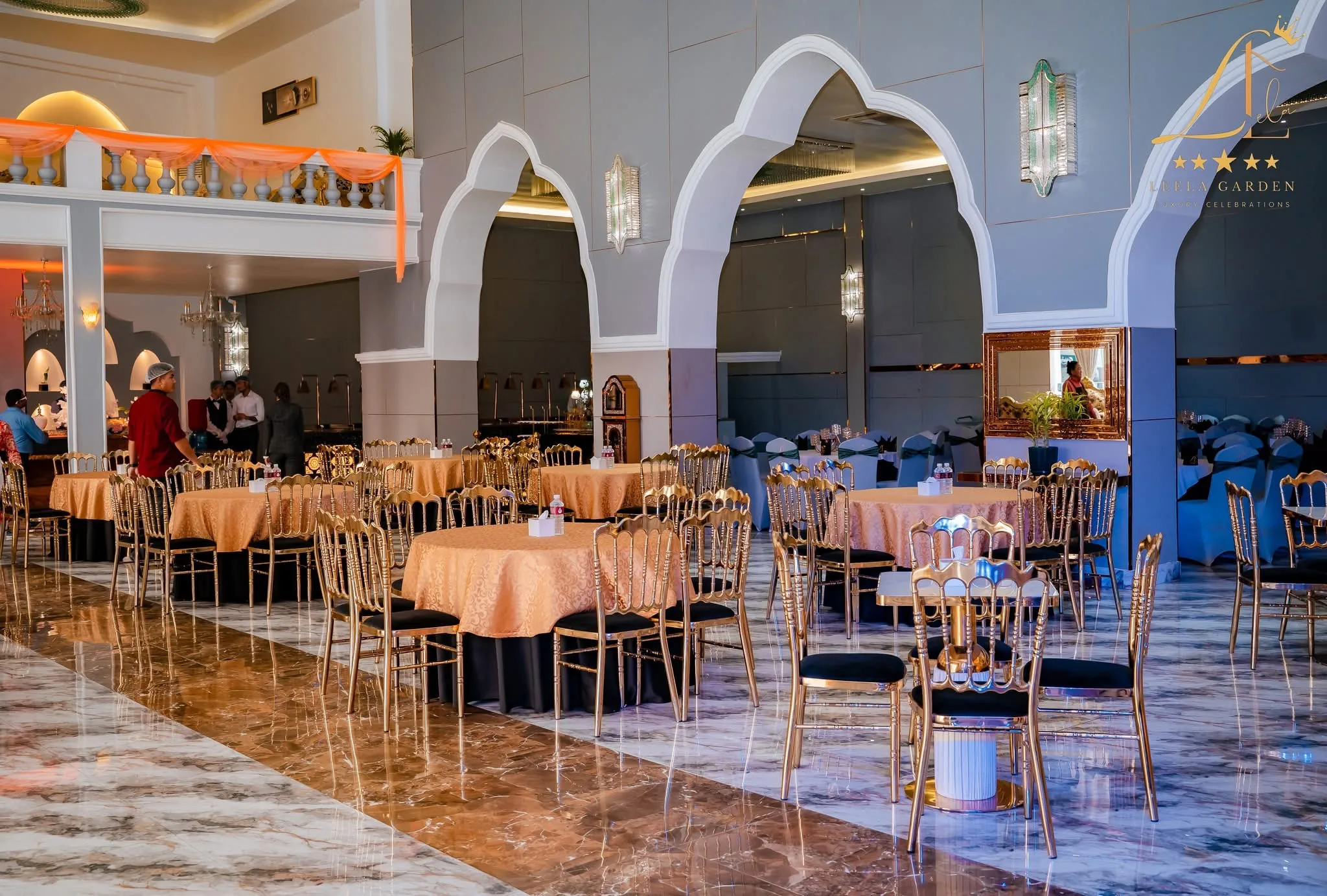 The hall between its white arched alcoves, round tables in gold cloth with chiavari chairs.
