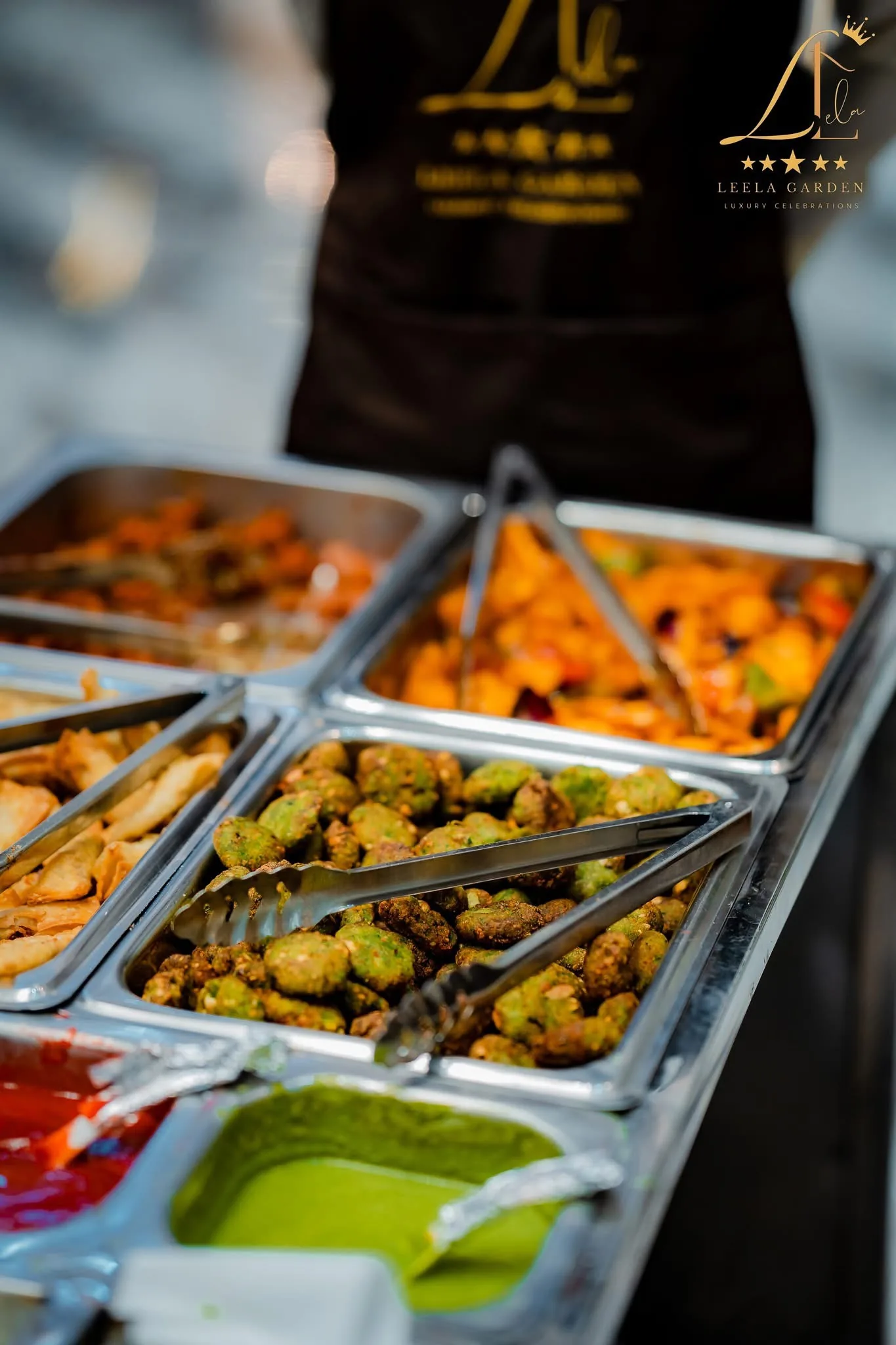 Buffet trays of fried snacks under service lighting.