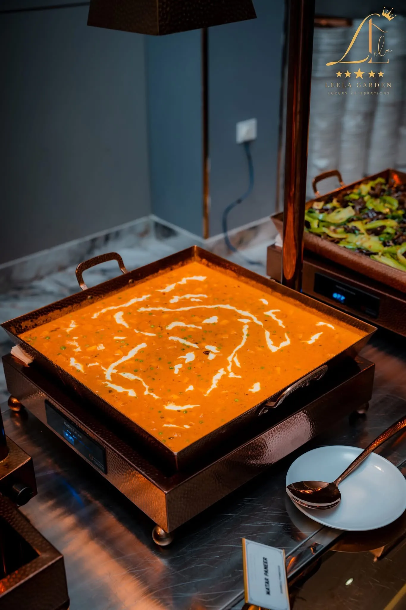 A copper serving tray of curry finished with a swirl of cream.