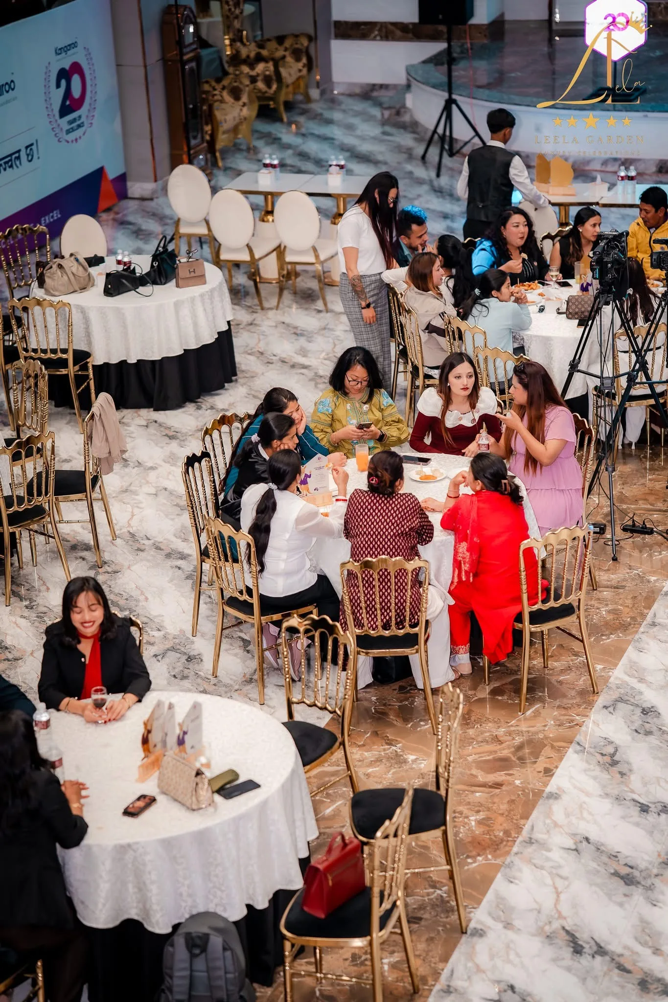 A group of guests seated together at a round table on gold chiavari chairs.