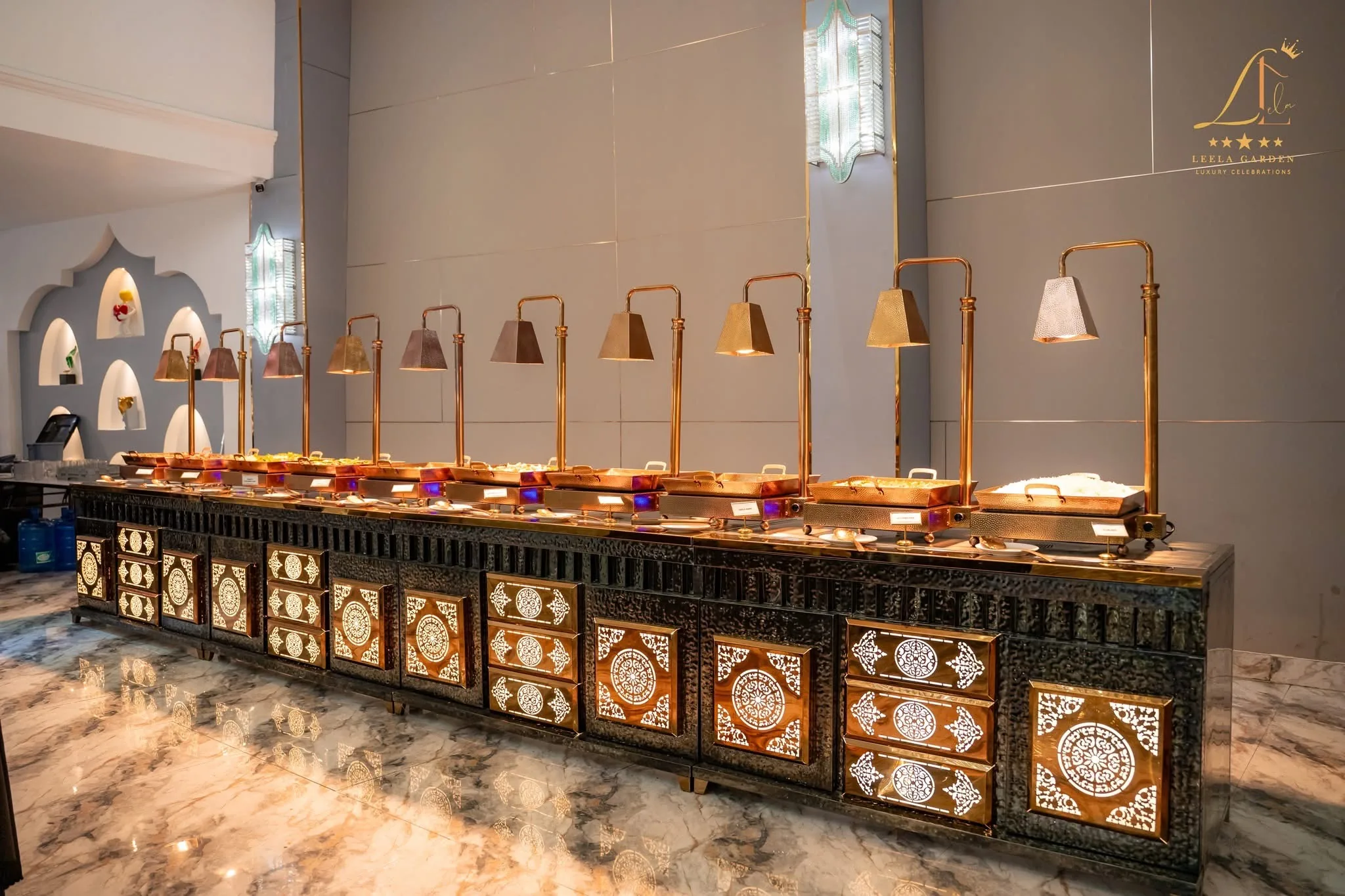 A long, glimmering buffet counter with inlaid panelling, lined with brass service lamps.