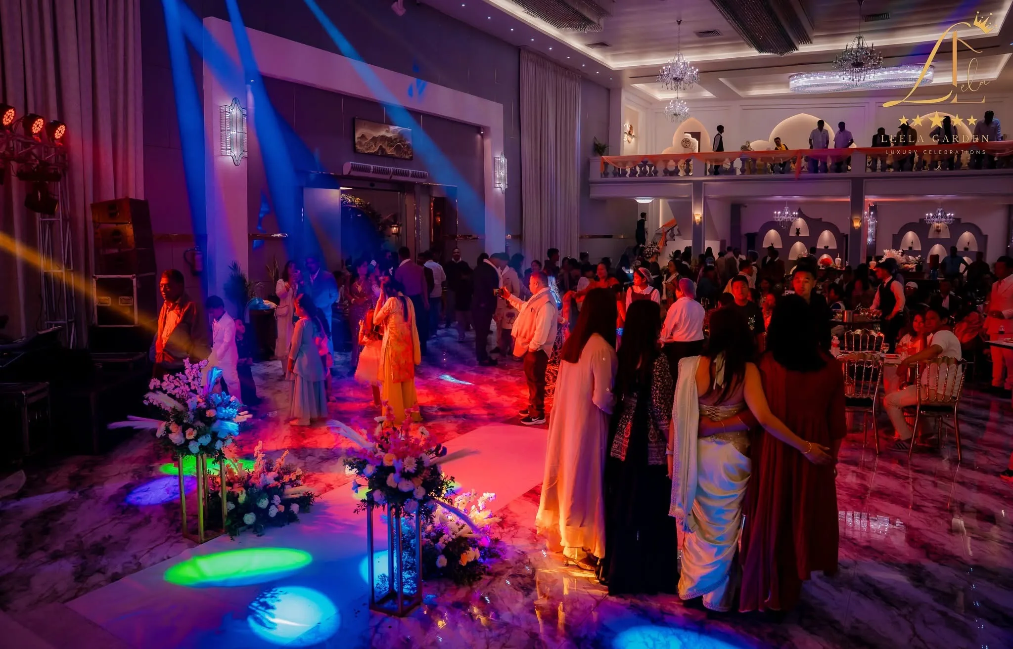 Guests dancing under coloured stage lighting, the floor washed pink and green.