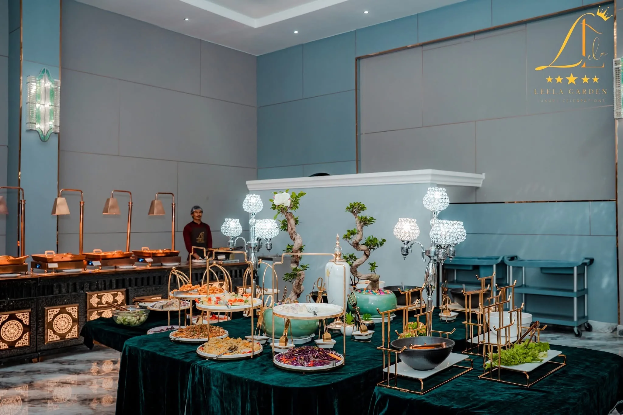 A buffet laid on deep green velvet, tiered stands and copper lamps above the dishes.