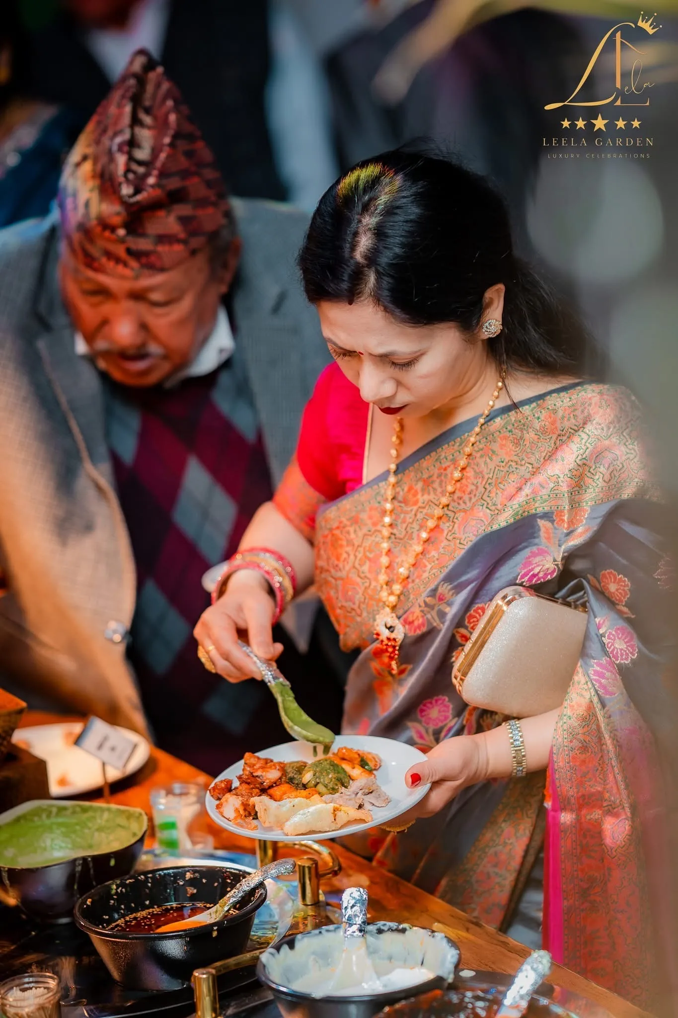 A guest in a patterned sari serving herself from the buffet.