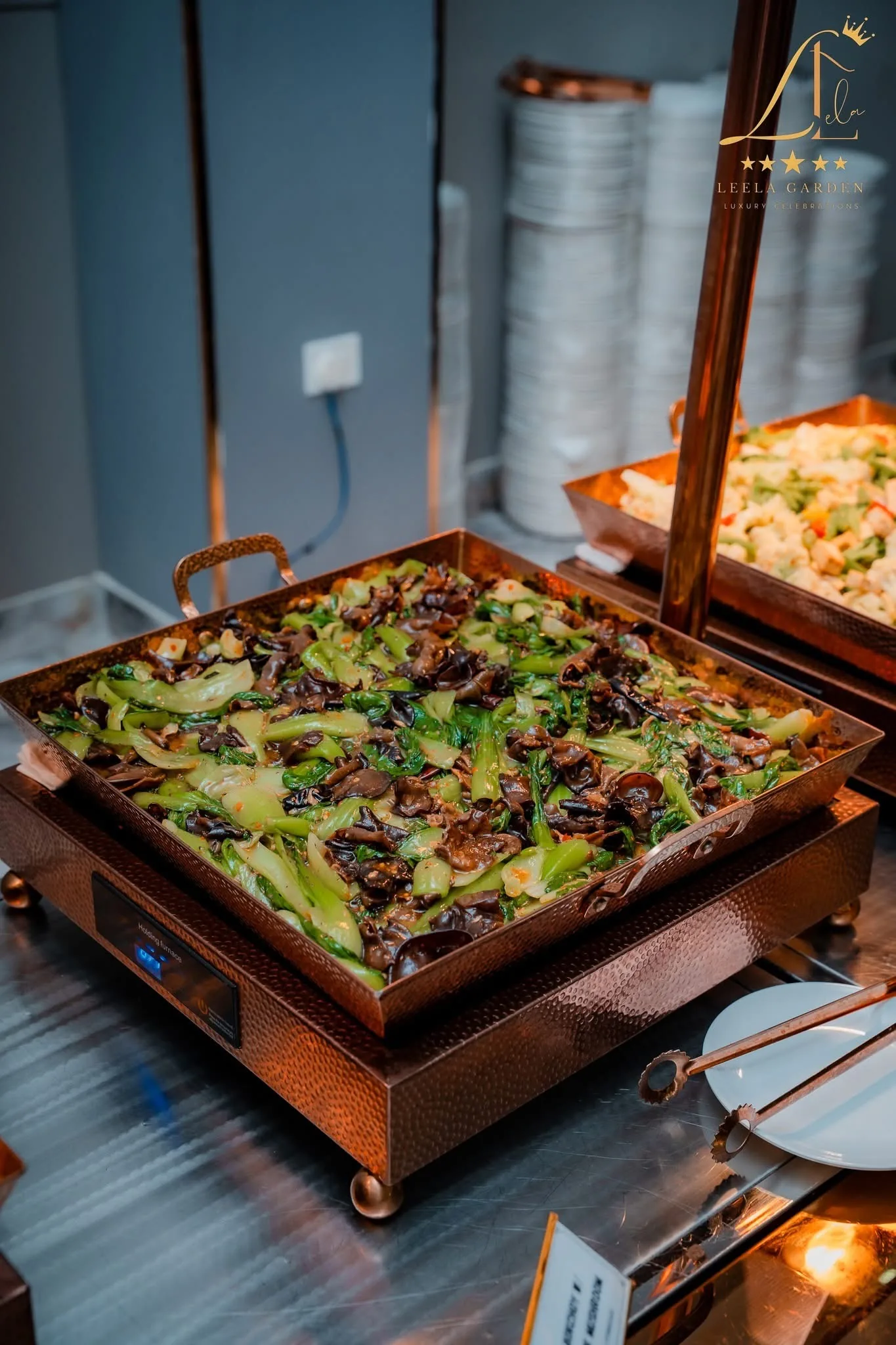 A copper tray of stir-fried greens on the buffet line.