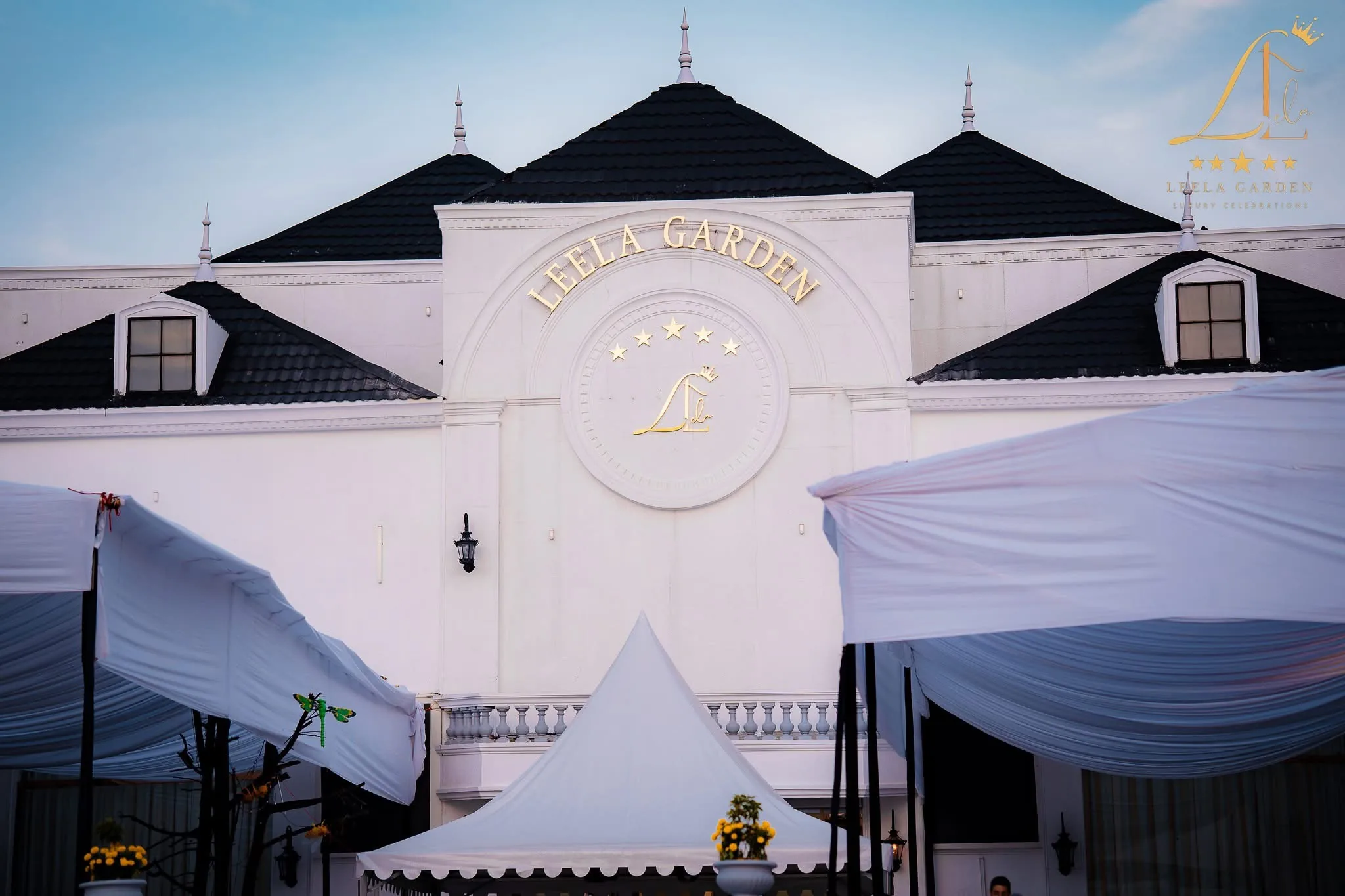 The white facade and black mansard roof at night, a marquee pitched beside the entrance.