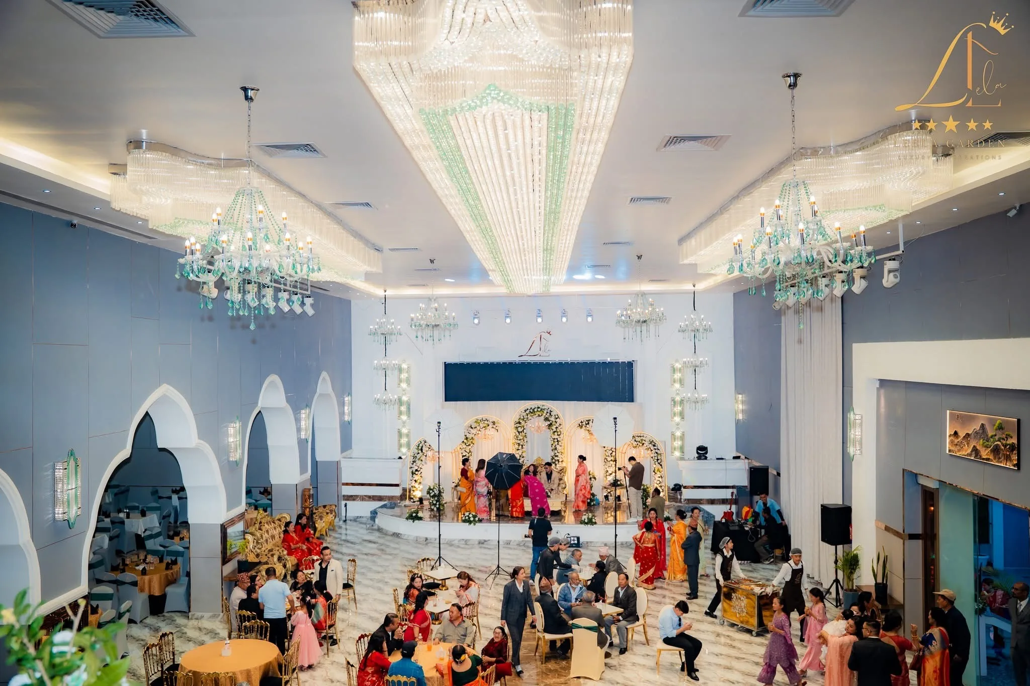 The hall seen from the balcony: chandeliers, the lit stage and a crowd filling the floor.